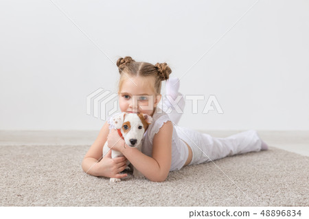 people, children and pets concept - little child girl lying on the floor with cute puppy Jack 48896834