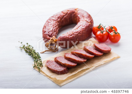 Food, cuisine and horsemeat concept - Close up of meat sausage with tomatoes and pepper on kraft 48897746