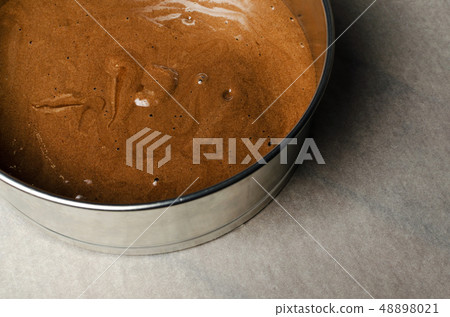 Cake pan with chocolate batter and wooden spoon close up on dark wooden background. Cake pan with chocolate batter and wooden spoon close up on dark wooden background. 48898021