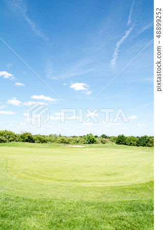高爾夫球場在初夏在與軌跡綠色和地堡的藍天下與藍旗信號 48899252