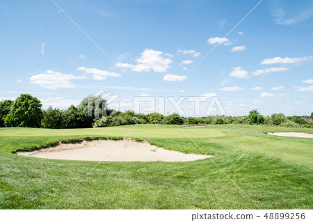 Golf course in early summer under blue sky Green and bunker with blue flag 48899256
