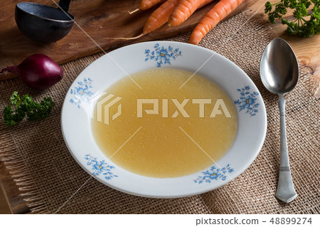 Chicken stock in a white plate with vegetables  48899274
