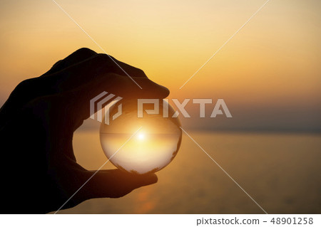 Crystal in silhouette hand with sunset sky at the 48901258