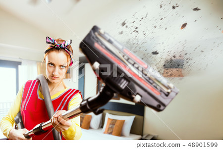 Angry housewife in apron with vacuum cleaner Angry housewife in apron with vacuum cleaner 48901599