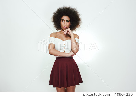 What should i do? Thoughtful afro american woman is holding hand on her chin, thinking and looking 48904239