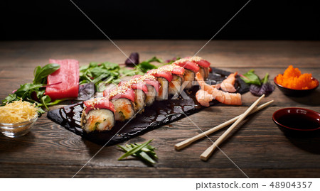 Serving sushi rolls and other traditional japanese and asian food on a table 48904357