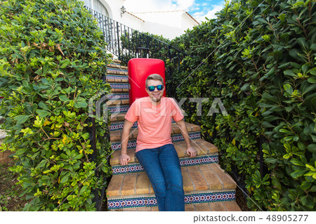 Holiday, travelling and people concept - man with red travel suitcase sitting on stairs his home Holiday, travelling and people concept - man with red travel suitcase sitting on stairs his home 48905277