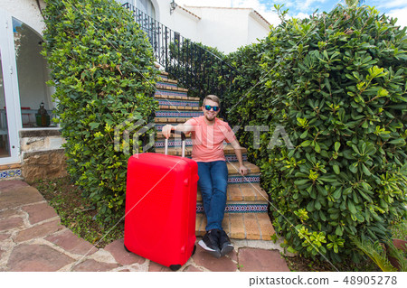 Holiday, travelling and baggage concept - young man with suitcase sitting on stairs Holiday, travelling and baggage concept - young man with suitcase sitting on stairs 48905278