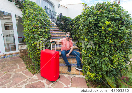Holiday, travelling and baggage concept - young man with suitcase sitting on stairs Holiday, travelling and baggage concept - young man with suitcase sitting on stairs 48905280