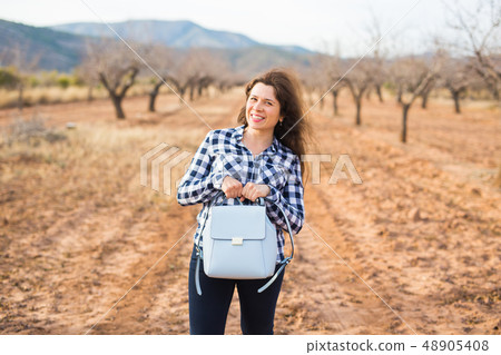 Trip, fashion and people concept - happy young woman walking with small bag and smiling over the 48905408