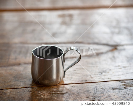 stainless steel cup on wood table 48909840
