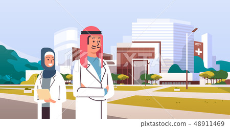 arabic couple man woman doctors in hijab and white uniform standing together in front of hospital 48911469