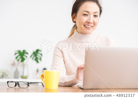 看便攜式計算機的資深婦女在屋子裡 看便攜式計算機的資深婦女在屋子裡 48912317