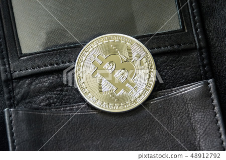Bitcoin metal coin laying on leather wallet 48912792