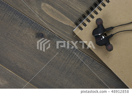 earphones and notebook on wood desk. 48912858