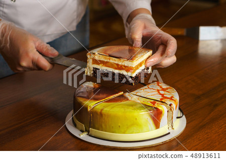 Confectioner cuts dacquoise cake in mirrored Confectioner cuts dacquoise cake in mirrored 48913611