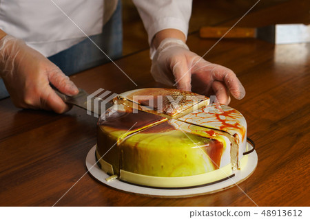 Confectioner cuts dacquoise cake in mirrored Confectioner cuts dacquoise cake in mirrored 48913612