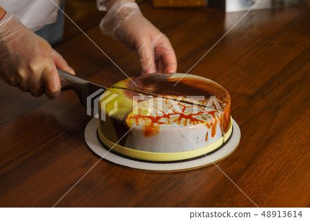 Confectioner cuts dacquoise cake in mirrored Confectioner cuts dacquoise cake in mirrored 48913614