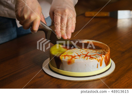 Confectioner cuts dacquoise cake in mirrored Confectioner cuts dacquoise cake in mirrored 48913615