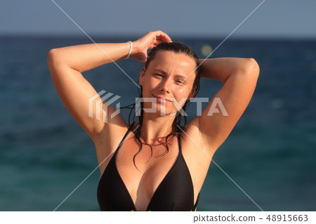 Wet young woman in swimsuit on beach Wet young woman in swimsuit on beach 48915663
