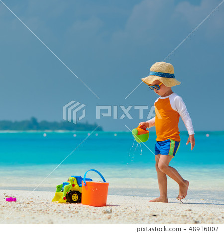 Three year old toddler playing on beach 48916002