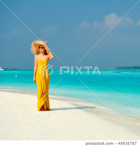 Woman in dress walking on tropical beach 48916787