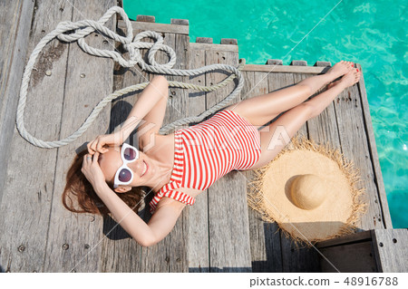 Woman in one-piece swimsuit on wooden jetty 48916788