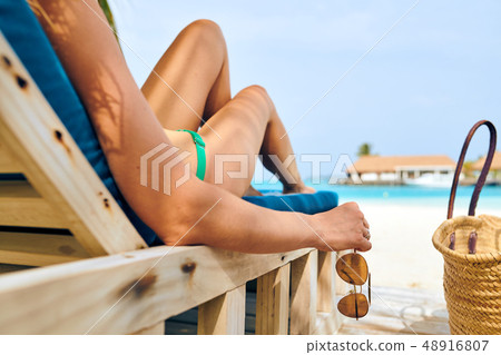 Woman at beach on wooden sun bed loungers 48916807