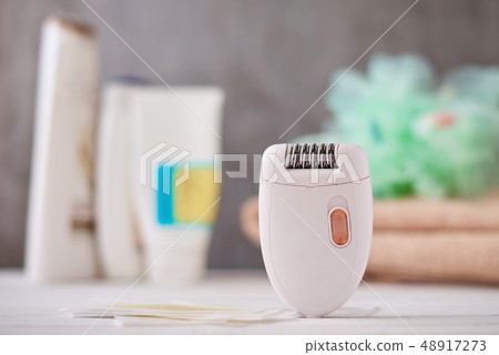 Epilator and wax strips on background with towel Epilator and wax strips on background with towel 48917273