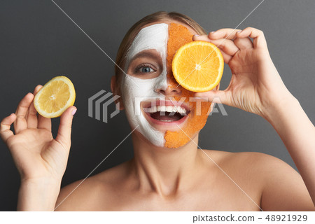 Emotional woman putting slices of fruit on her face and looking excited 48921929