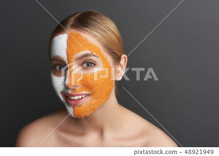 Beautiful woman with two colored facial masks smiling Beautiful woman with two colored facial masks smiling 48921949