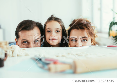 Joyful family looking from table with cookies Joyful family looking from table with cookies 48923239