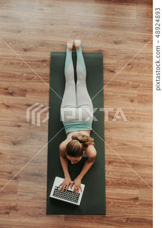 Top view woman laying on yoga mat with laptop 48924893
