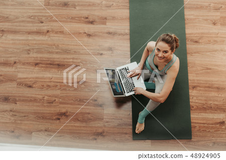 Woman sitting with laptop on bending leg 48924905