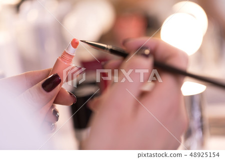 Cropped photo of female arms with liquid lipstick and brush Cropped photo of female arms with liquid lipstick and brush 48925154