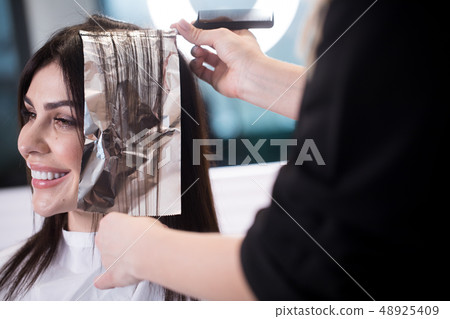 Smiling brunette woman dying her hair at the beauty salon Smiling brunette woman dying her hair at the beauty salon 48925409