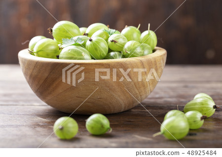 Ripe green gooseberries in a wooden bowl. Ripe green gooseberries in a wooden bowl. 48925484