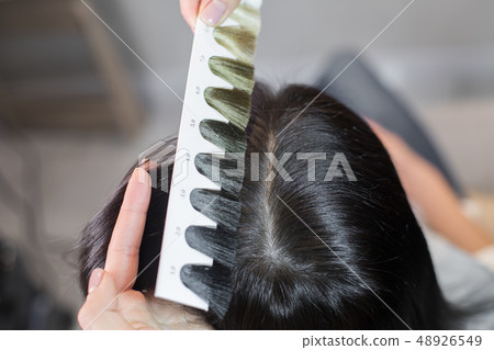 Stylist selecting new hair color for client in beauty saloon Stylist selecting new hair color for client in beauty saloon 48926549