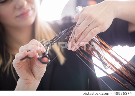 Close up of clean hair with scissors in arms of stylist Close up of clean hair with scissors in arms of stylist 48926574
