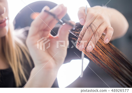 Close up of clean hair with scissors in arms of stylist Close up of clean hair with scissors in arms of stylist 48926577