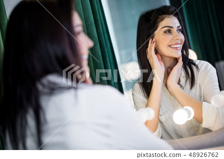 Beautiful woman in white bathrobe looking at mirror indoors Beautiful woman in white bathrobe looking at mirror indoors 48926762