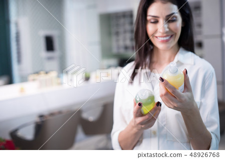 Half length of happy lady keeping cosmetics in hands on blurred background Half length of happy lady keeping cosmetics in hands on blurred background 48926768