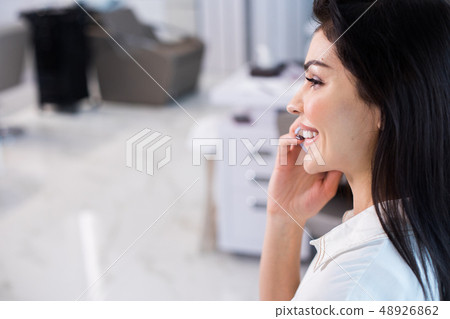 Happy Caucasian lady holding smartphone at her ear in beauty saloon Happy Caucasian lady holding smartphone at her ear in beauty saloon 48926862