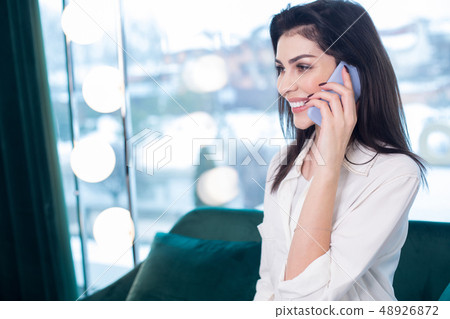 Happy Caucasian woman holding smartphone at her ear Happy Caucasian woman holding smartphone at her ear 48926872