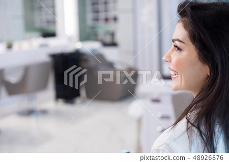 Side view of charming brunette woman smiling in saloon Side view of charming brunette woman smiling in saloon 48926876