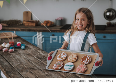 Little girl showing egg shaped cookies on pan 48927695