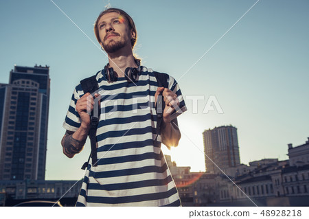 Waist up of a pleasant young man standing in urban settings 48928218