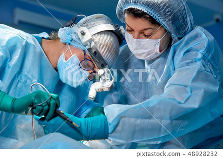 Team of surgeons makes an invasive operation. Portrait of surgeons close-up. Work with a coagulating 48928232