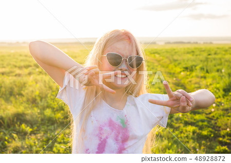 Indian holidays, fun and childhood concept - girl in glasses smiling, having fun on the holi 48928872