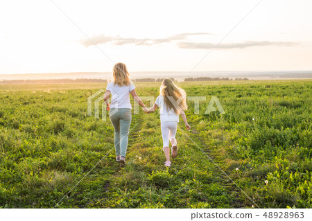 Family, summer and holiday concept - Back view of mother holding her daughter's hand running towards Family, summer and holiday concept - Back view of mother holding her daughter's hand running towards 48928963